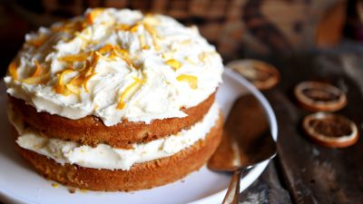 An 2-layerorange drizzle cake with buttercream in the middle and on top.