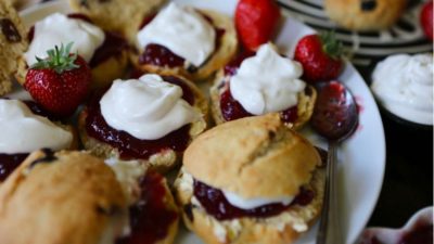 A plate of scones with cream and jam.